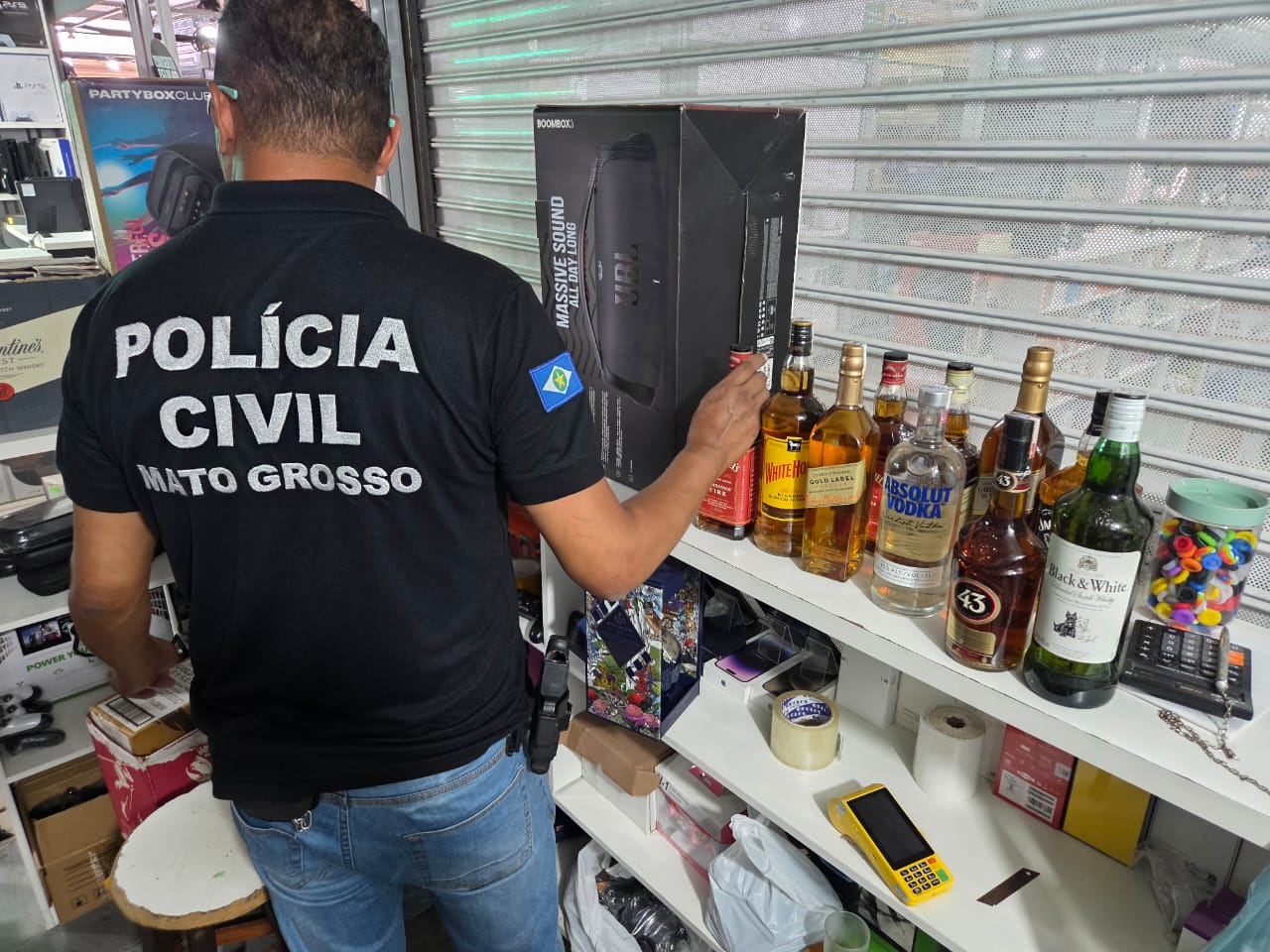 Garrafas de bebidas destiladas com indícios de falsificação apreendidas durante operação da Polícia Civil no Shopping Popular de Cuiabá.