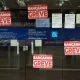 Cartazes vermelhos de bancários anunciam a greve da Caixa na porta de vidro de agência fechada no Distrito Federal