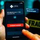 Celular mostra tela de contestação do MED Pix com botão vermelho; ao fundo, silhueta desfocada e fita amarela de fraude